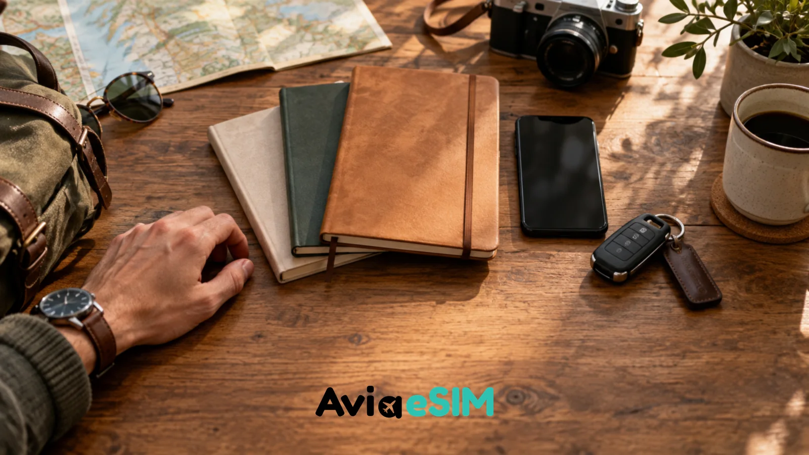 Reise-Notizbücher, Smartphone und Autoschlüssel auf einem Holztisch bei der Planung einer Balkan-Rundreise